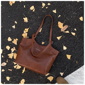 Detail of dark brown leather tote bag with Mihuadoudou text on autumn leaves