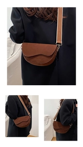 Detail view of a vintage brown suede saddle bag with a wide woven shoulder strap