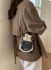 Detail of snake skin texture bucket bag with pearl handle and golden chain strap