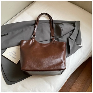 Close-up of brown glossy leather tote bag with silver buckles and large capacity
