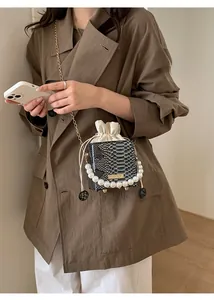 Detail view of pearl handle and crocodile texture on mini bucket bag with chain strap