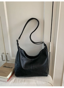 Detail of black retro hobo bag with vertical stitching on white wooden background