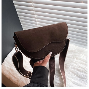 Detail view of dark brown faux suede saddle bag with wide strap and gold hardware