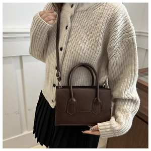Brown leather handbag shown on model with shoulder strap and gold hardware detail