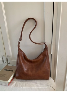 Detail of a brown PU leather hobo bag with a vertical seam and adjustable strap
