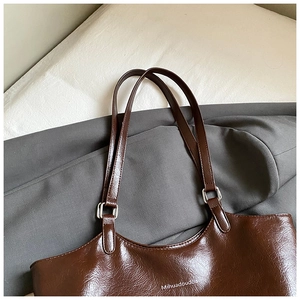 Detail of dark brown leather tote bag with fine wrinkled texture and silver hardware