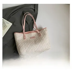 Detailed close-up of cream quilted tote bag with pink leather trim and textured fabric finish