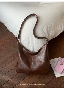 Detail of dark brown retro PU leather hobo bag with vintage texture and stitched seams