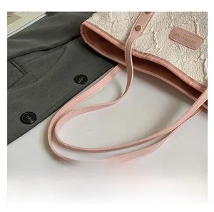 Close-up of white quilted texture fabric tote with pink leather trim and gold studs
