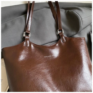 Close-up of vintage dark brown tote bag showing textured leather and silver metal buckles