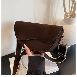 Detail of dark brown suede saddle bag with wavy flap and stylish wide strap