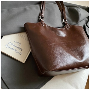 Detail of dark brown glossy leather tote bag with silver hardware and logo print