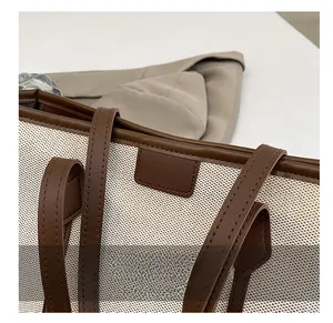 Détail du sac cabas en toile et cuir marron montrant les coutures de haute précision