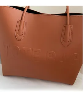Close-up of brown leather tote bag with TOTE BAG embossed design and dual handles