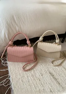 Detail of woven texture and knot handle on pink and cream PU leather crossbody bags