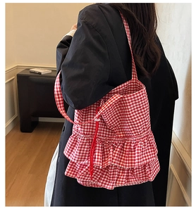 Detail of red and white checkered tote bag featuring ruffle design and drawstring closure