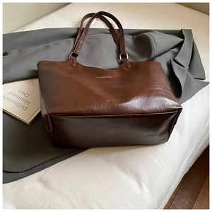 Detail of dark brown leather tote bag showing smooth oil wax texture and silver metal hardware