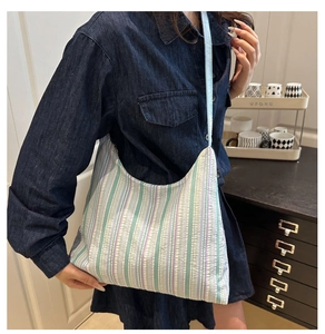 Détail du sac hobo avec texture plissée rayée et fine bandoulière bleue élégante
