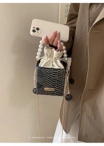 Detail of snake print bucket bag with large pearl handle and gold chain strap