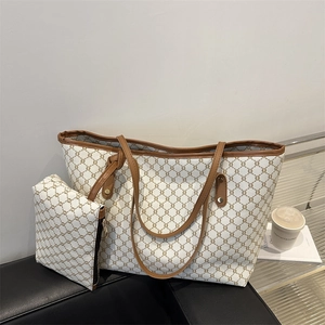 Detail of vintage canvas tote bag set with monogram print and leather trim on a sofa