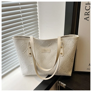Detailed texture of a white oversized tote bag with premium embossed fabric and leather label