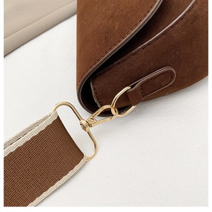 Détail du sac besace en daim marron foncé avec fermoir doré et bandoulière rayée