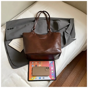 Top view of dark brown leather tote bag showing large capacity with tablet for scale