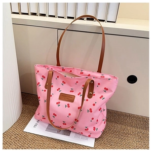 Detail of pink cherry print tote bag featuring brown faux leather straps and metal rivets
