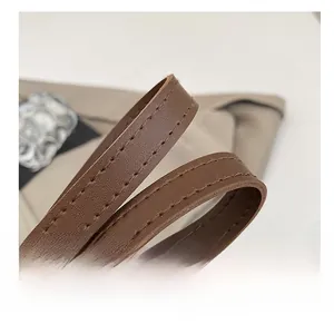 Détail de bandoulière en cuir marron avec double surpiqûre et boucle métallique chic
