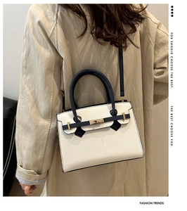 Borsa a mano bicolore con chiusura dorata abbinata a un classico trench beige
