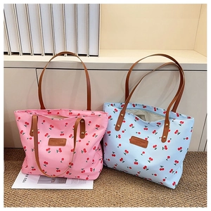 Detail of pink and blue canvas cherry print tote bags with brown leather shoulder straps
