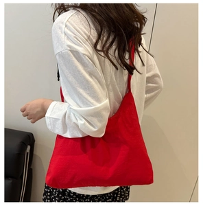 Vue arrière du mannequin portant un grand sac à bandoulière rouge en nylon léger