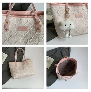 Detail view of large tote bag with embossed fabric, pink straps and plush cloud charm