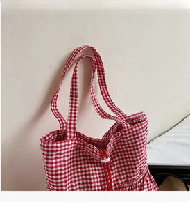 Close-up of red and white plaid fabric tote bag with functional drawstring closure detail