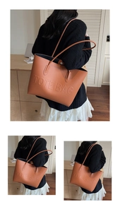Detail of large brown tote bag with embossed TOTE BAG text and smooth PU leather texture