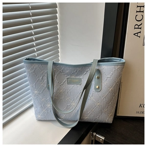Close-up of light blue tote bag with floral embroidery and textured fabric detail