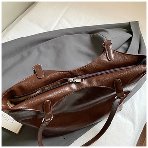 Detail of dark brown leather tote showing shiny oil wax texture and silver zipper