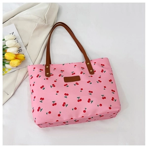 Detail shot of pink cherry print tote bag with brown handles and elegant tulip decoration