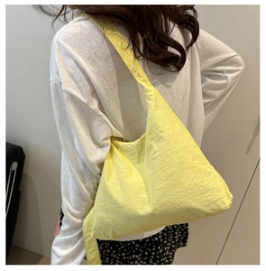 Modèle portant un sac cabas léger en nylon jaune pâle avec une texture plissée élégante