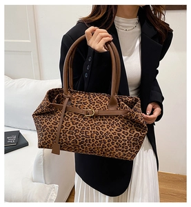 Detail view of leopard print tote bag featuring brown leather handles and golden buckle