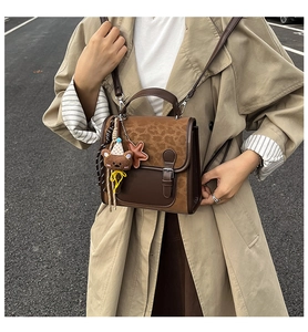 Close-up of retro two-tone crossbody bag with bear charm on a trench coat model