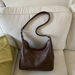 Brown vintage faux leather hobo shoulder bag with wrinkled texture on a beige sofa
