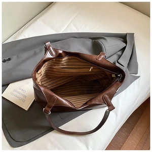 Close-up of large brown tote bag interior featuring striped lining and zipper pocket