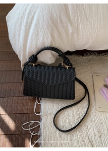 Close-up of black woven square bag with sophisticated V-shaped texture on white rug