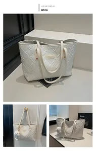 Detail of white tote bag with woven texture, leather brand tag and cloud plush pendant