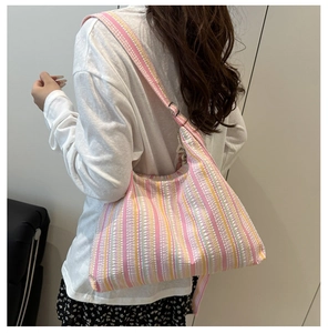 Détail d'un sac à main en toile rayée montrant le tissu texturé et la large bandoulière