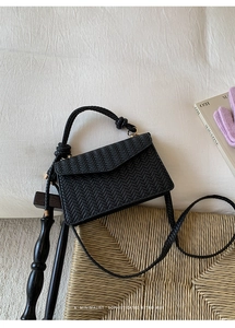 Detail of black woven texture on a minimalist retro crossbody bag with knotted handle