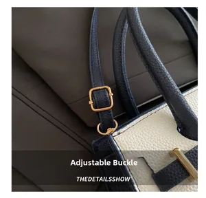 Dettaglio della fibbia dorata regolabile e pelle grana blu navy sulla borsa a mano