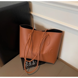 Dettaglio borsa tote in ecopelle marrone caramello con logo goffrato e spalline sottili