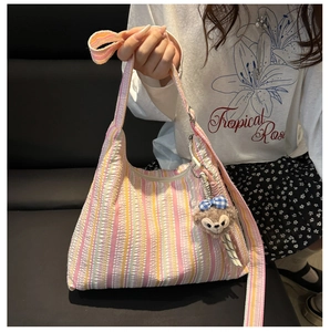 Détail du sac à bandoulière en toile rayée avec texture plissée et breloque ours en peluche